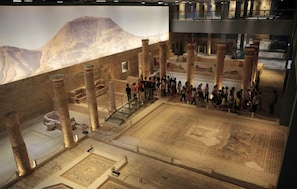 Vue intérieure d’un site archéologique ancien, avec des colonnes, un espace central ouvert et un escalier.