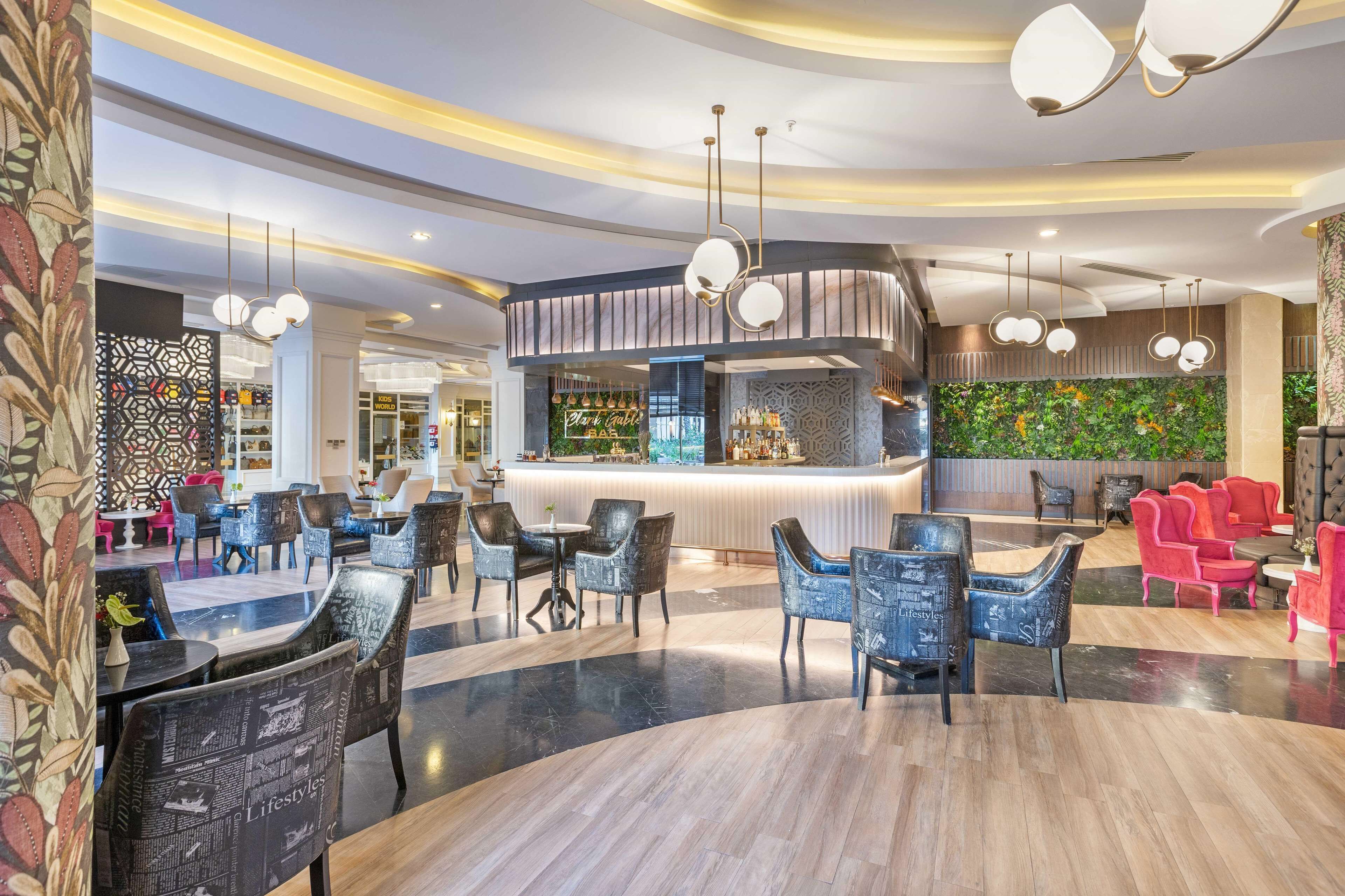 A modern hotel lobby with a bar area, seating arrangements, and decorative wall panels.