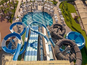 A water park with multiple slides and pools, surrounded by lounge areas and palm trees. - Kirman Belazur Resort & Spa - All Inclusive (Serik)