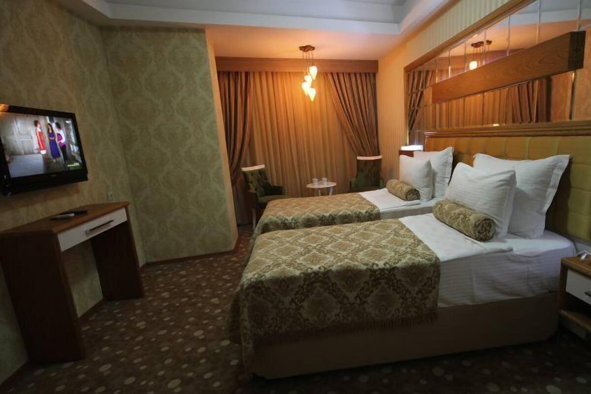 A hotel room with two beds, a desk, a TV, and a bedside table with a phone.