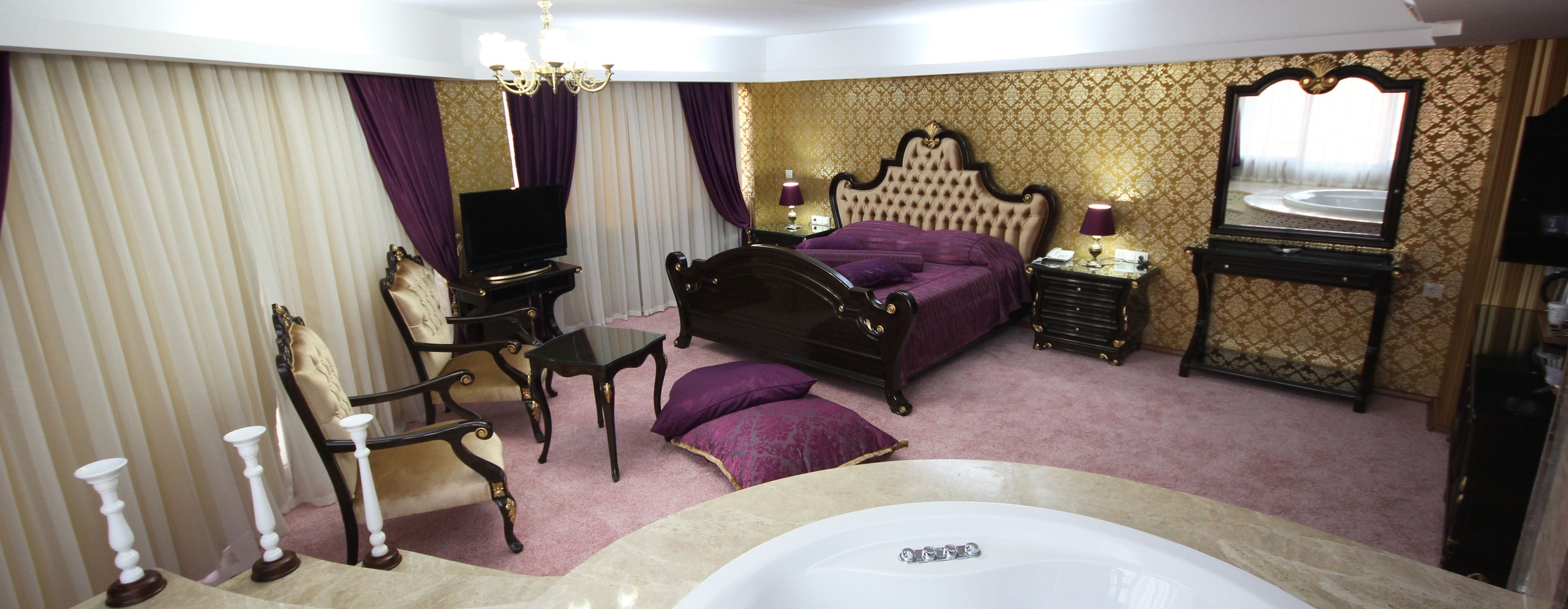 Une chambre à coucher avec un lit, une coiffeuse avec un miroir, une télévision et un lustre.