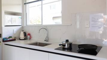 A modern kitchen with a double sink, a stove, and a window above the sink.