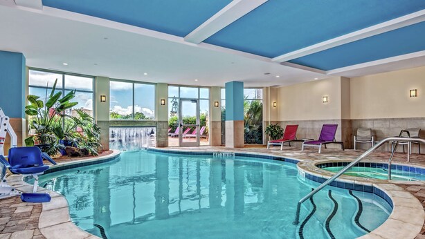 An indoor swimming pool with clear water, a waterfall feature, and lounge chairs. - Hilton Garden Inn Victoria (Victoria)