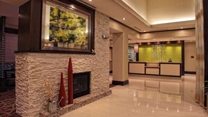 A lobby with a stone fireplace, a reception desk, and a large framed artwork. - Hilton Garden Inn Victoria (Victoria)