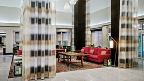A modern hotel lobby with a red sofa, a wooden coffee table, and a floor lamp. - Hilton Garden Inn Victoria (Victoria)