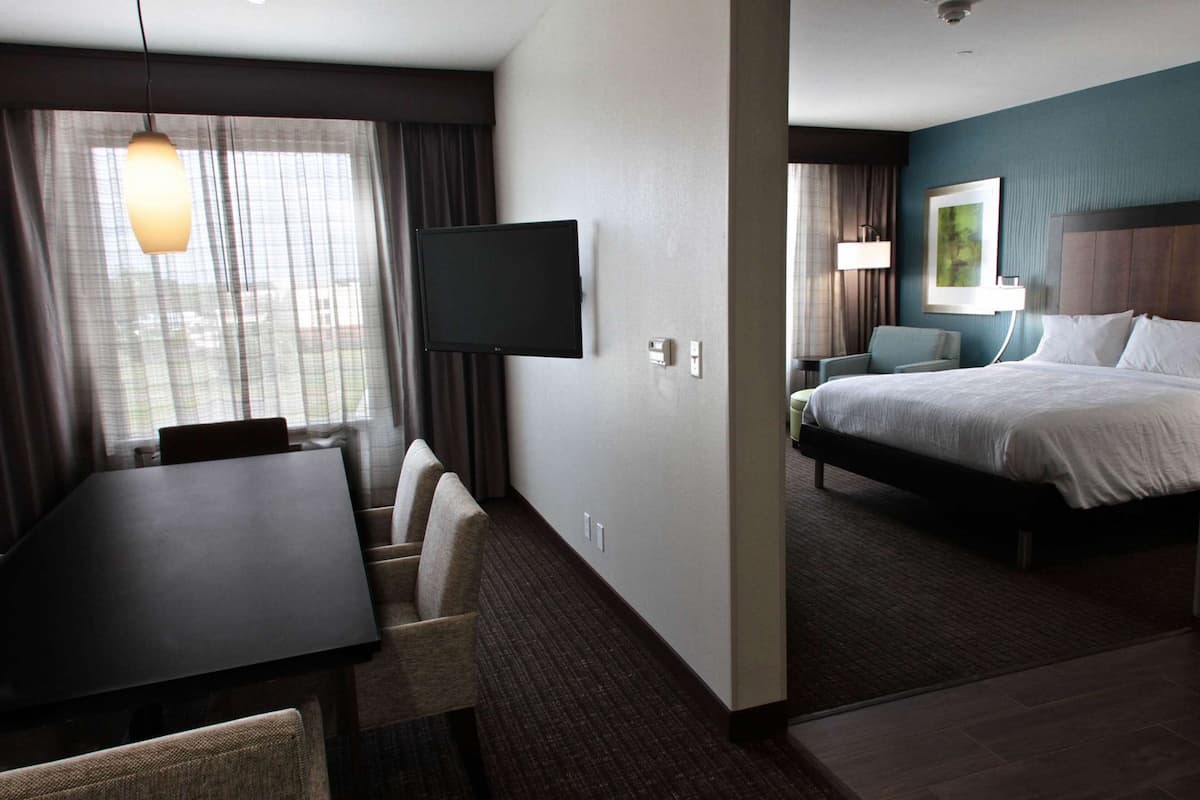 A hotel room with a bed, a TV, a dining table, and a chair.