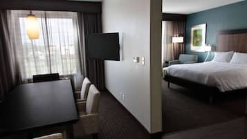 Ein Hotelzimmer mit Bett, Fernseher, Esstisch und Stuhl.