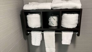 A bathroom with a towel rack holding several white towels. - Days Inn by Wyndham Calhoun GA I-75 and US-41 (Calhoun)
