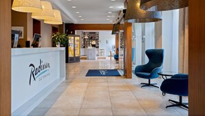 A reception area with a reception desk, modern chairs, and pendant lighting. - Radisson Hotel Old Town Riga (Riga)
