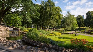 A park with a pond, stone walls, and various plants. - Radisson Hotel Old Town Riga (Riga)