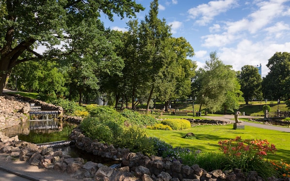 Un parque con un estanque, muros de piedra y diversas plantas.