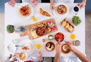 A breakfast setting with various dishes, including pancakes, croissants, and a fruit salad.