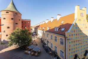 A historic building with a tower, a row of traditional houses with tiled roofs, and outdoor seating areas.