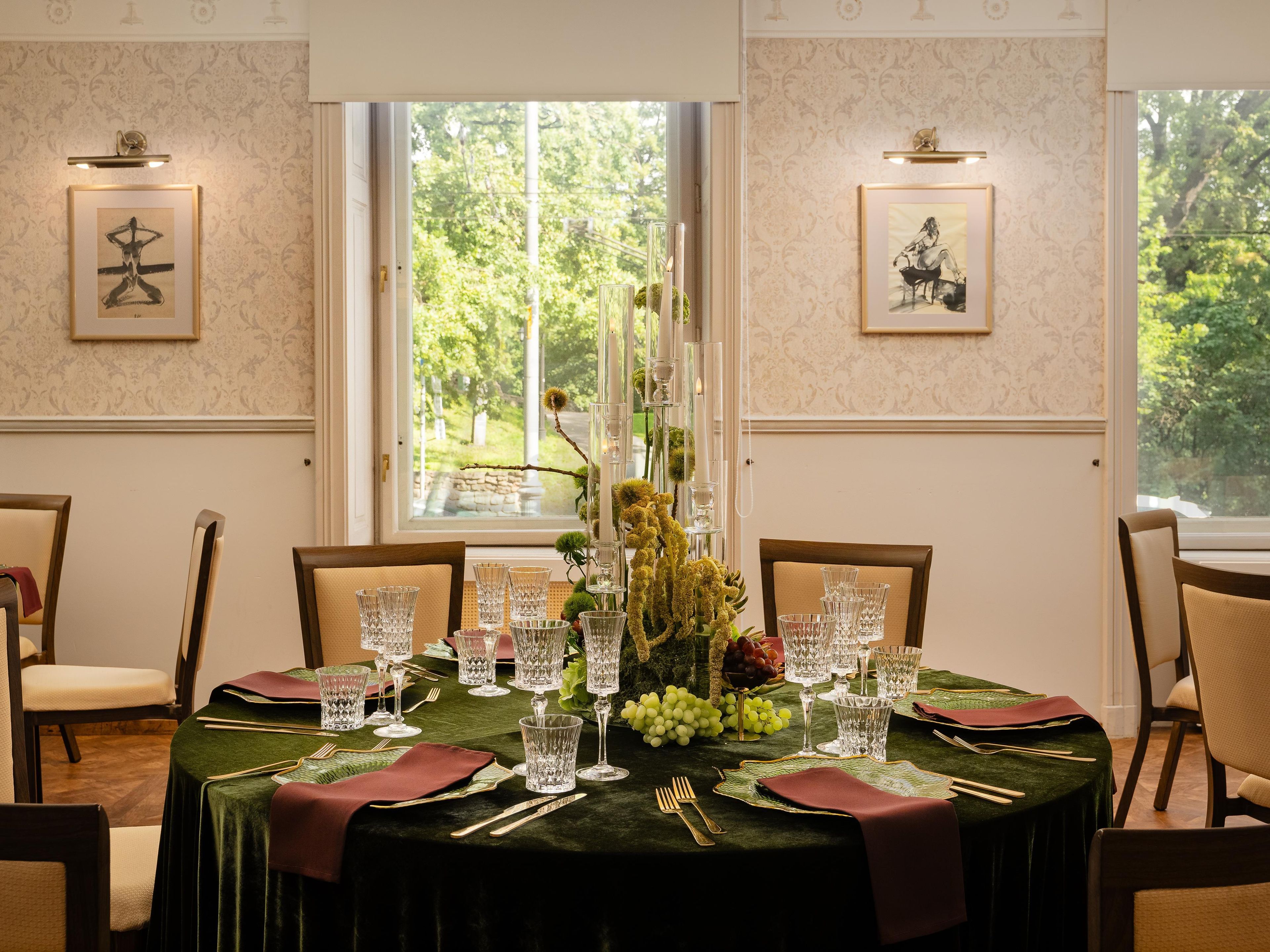 A dining table set with glassware, plates, and cutlery, with chairs around it.