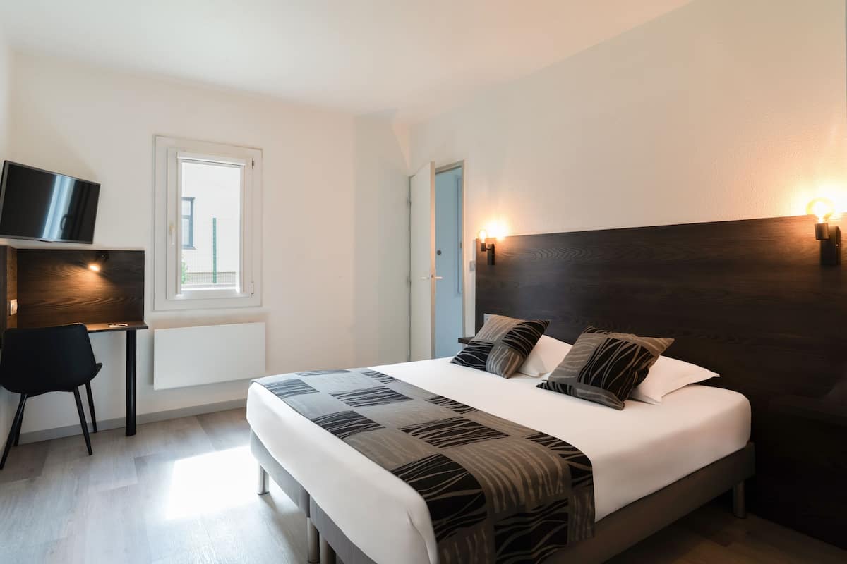 Ein Schlafzimmer mit Bett, Nachttischen, Fernseher und Fenster.