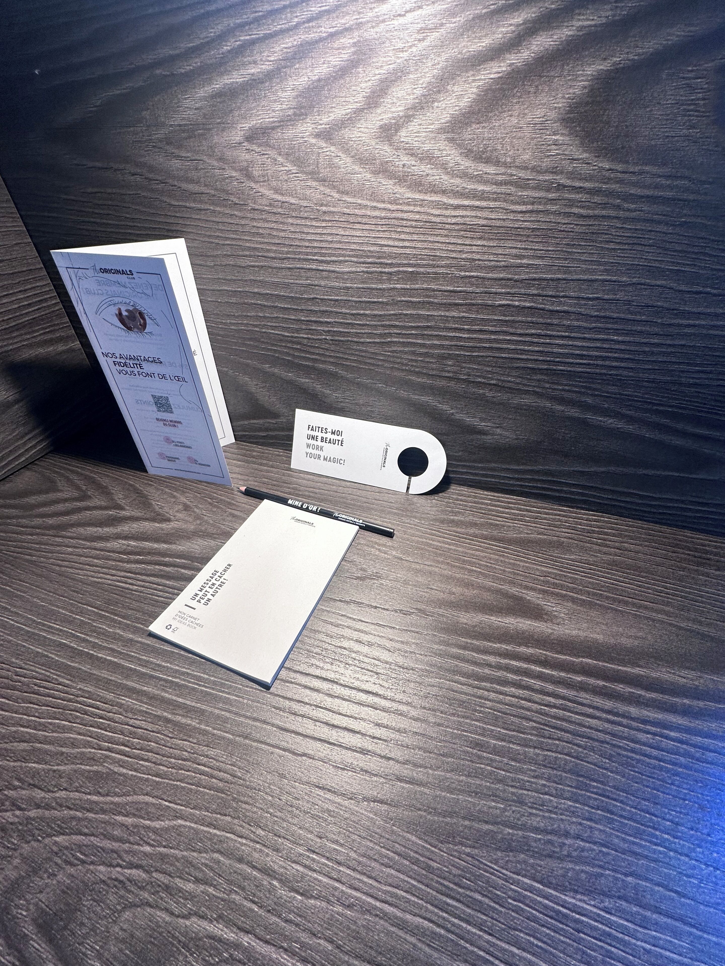 A wooden surface with a business card, a pen, and a booklet.