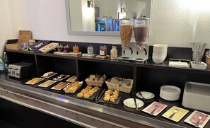 A buffet area with various food items, including pastries, bread, and condiments.