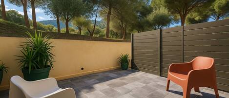An outdoor patio with two chairs, a low wall, and a gate.