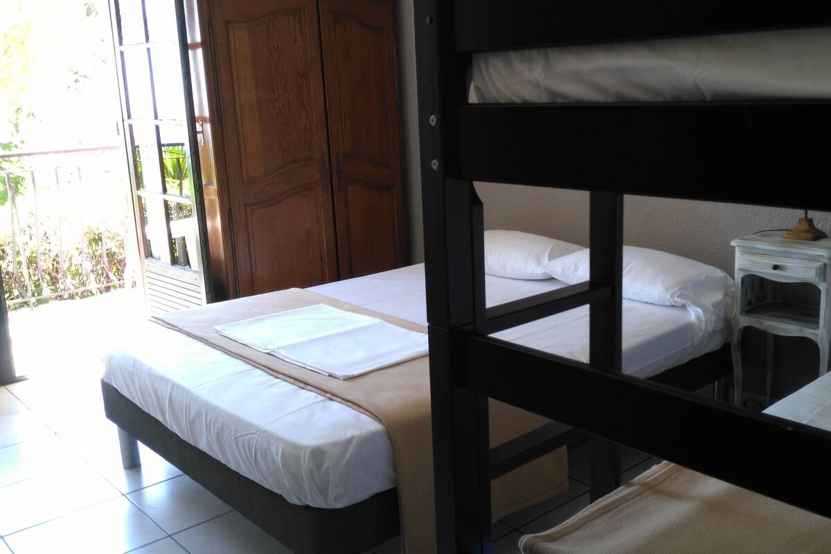 A room with bunk beds, a small bedside table with a lamp, and a wooden door.