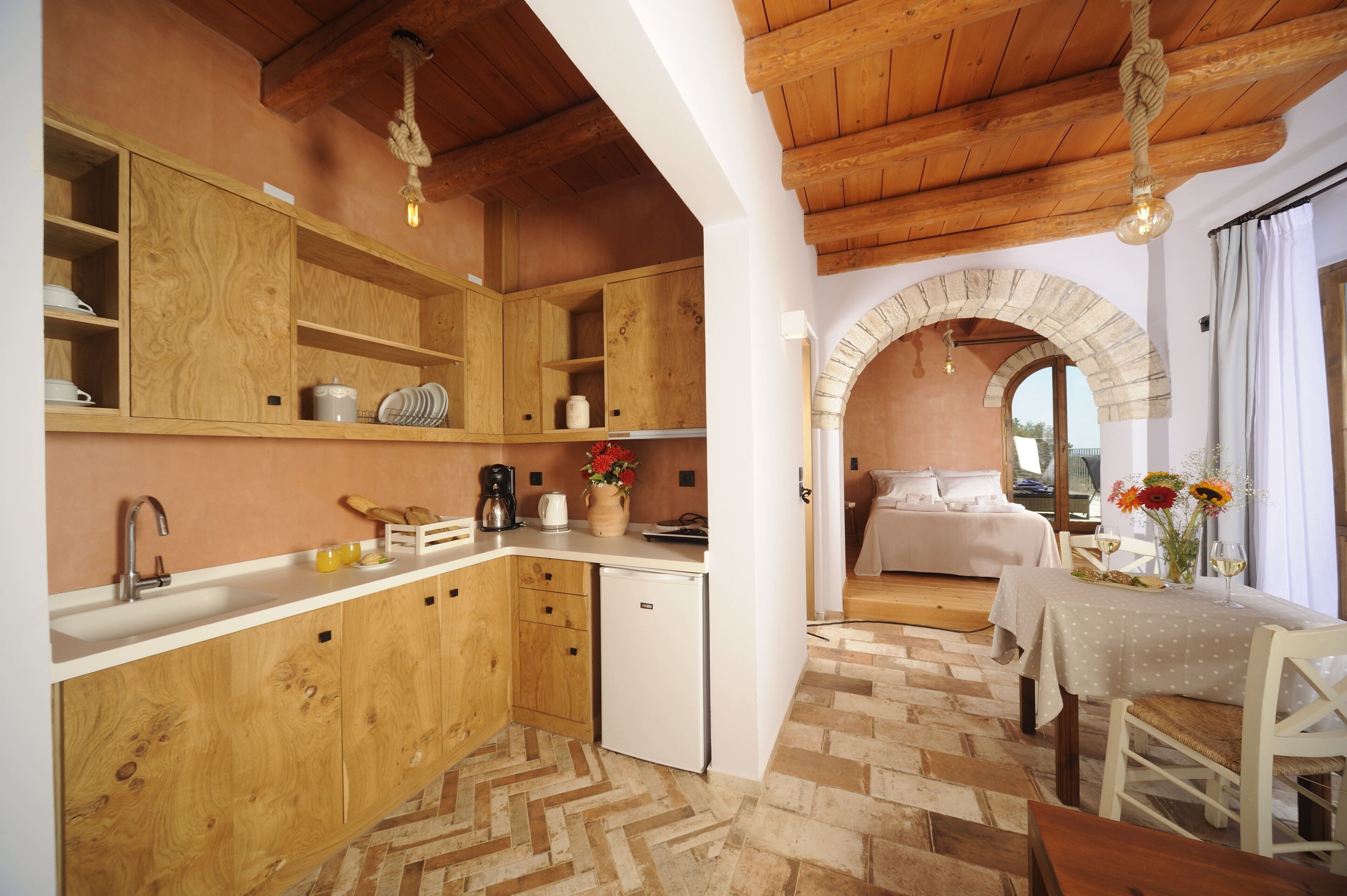 Uma cozinha com armários de madeira, bancada branca e piso em padrão herringbone.