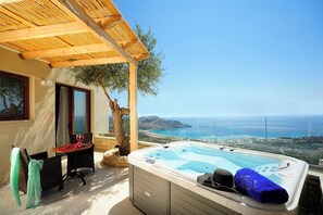 A hot tub with a view of the sea, a table with chairs, and a pergola. - Stefanos Village (Agios Vasileios)