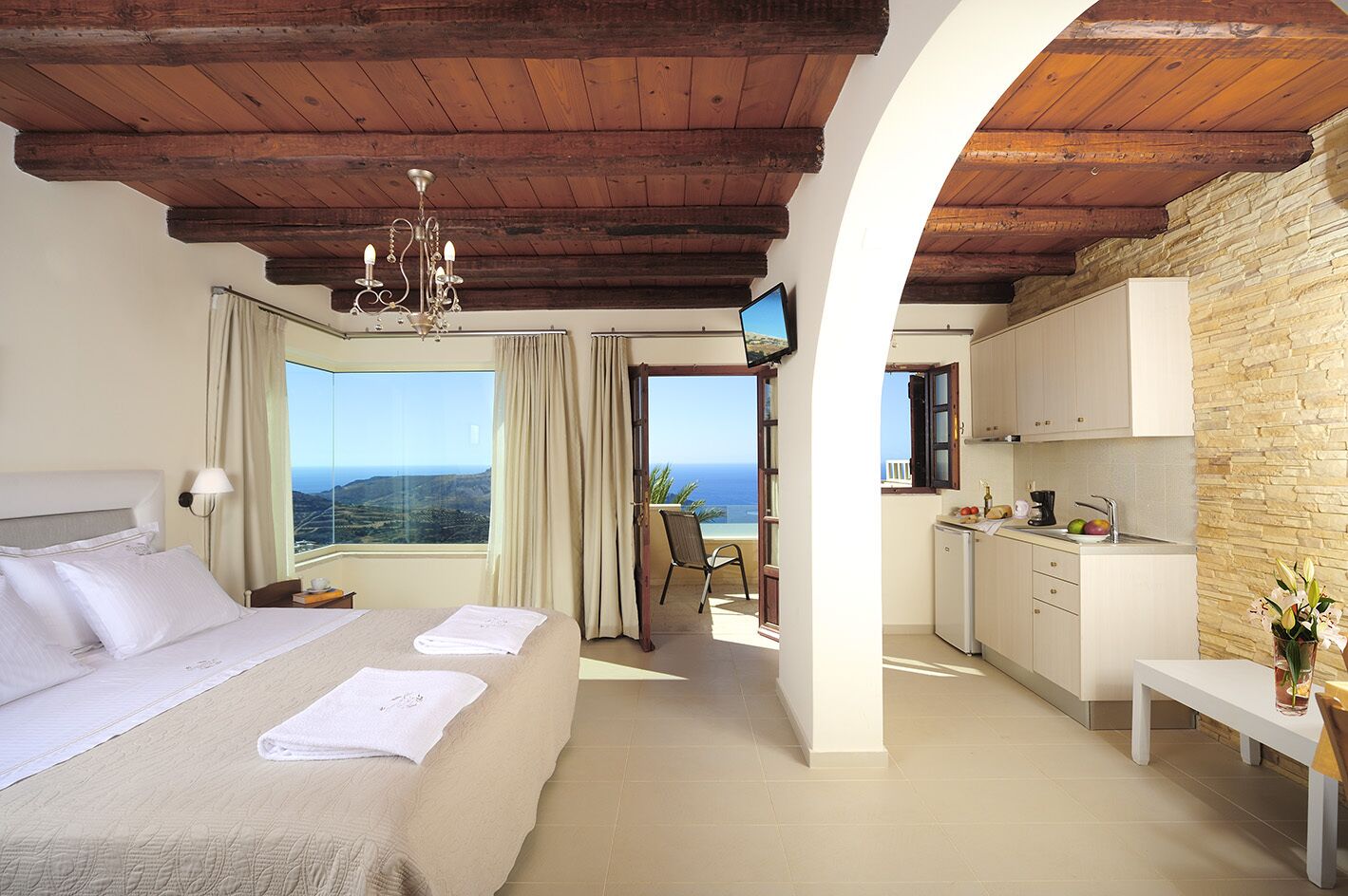 Un dormitorio con una cama grande, televisor y vista al mar.