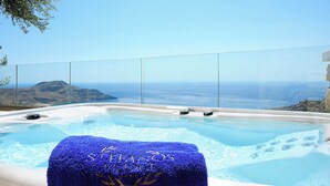 Un bain à remous offrant une vue dégagée sur l’océan et un paysage montagneux en arrière-plan.