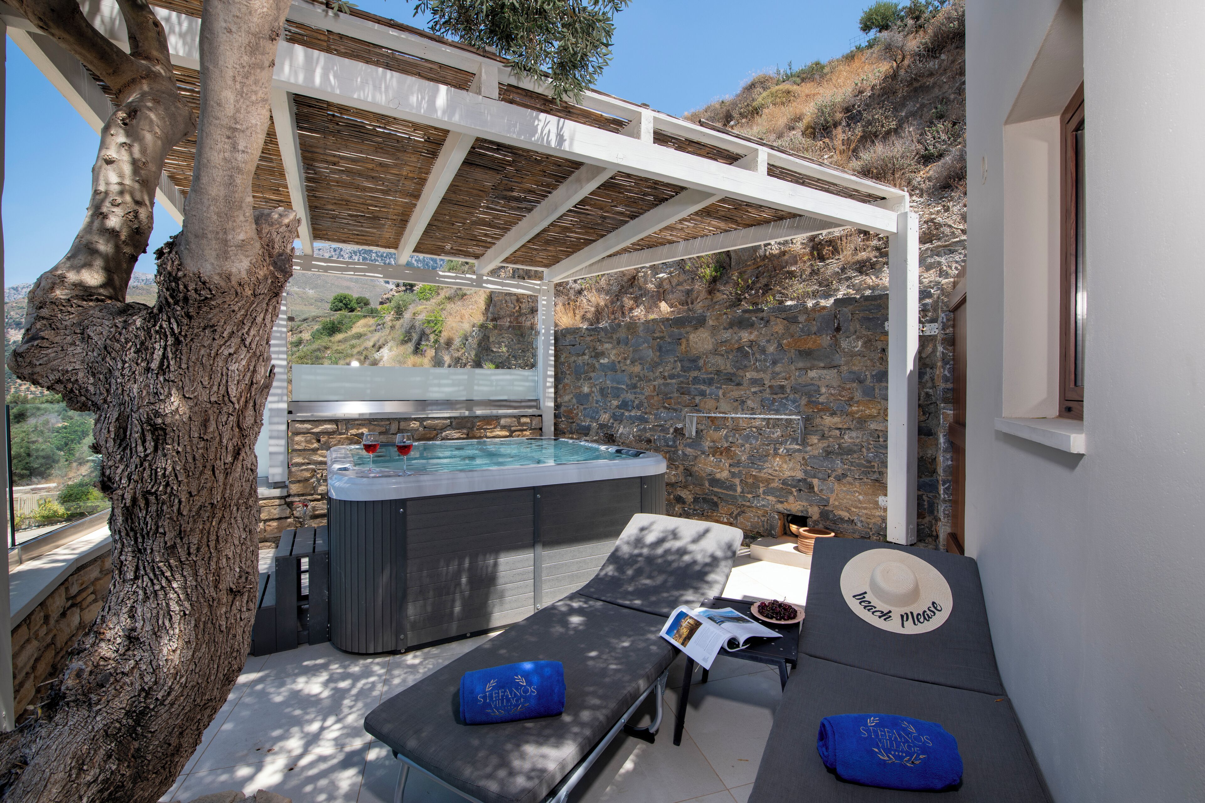 A spa area with a hot tub, lounge chairs, and a pergola.