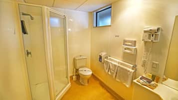 Une salle de bain avec une douche à parois de verre, des toilettes, un lavabo avec un miroir et un porte-serviettes.