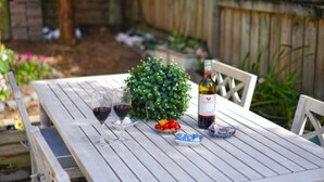 A wooden table with two wine glasses, a bottle of wine, and a small potted plant. - Ashwood Manor Motor Lodge (Hamilton)