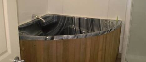 A small, enclosed hot tub with a wooden exterior and a black marble interior.