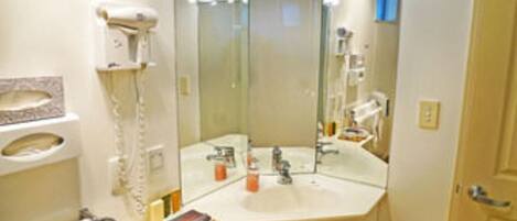 A bathroom with a white sink, mirror, and a hairdryer on the wall.