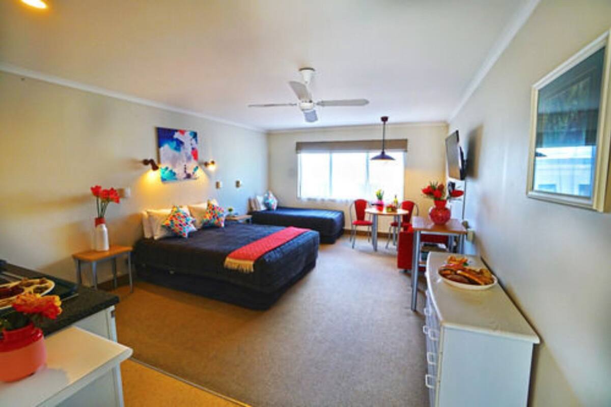 A hotel room with a bed, a desk, a chair, a television, and a window.