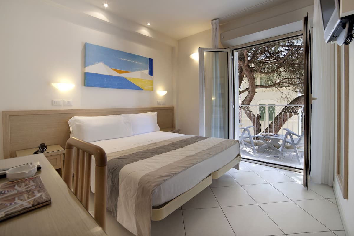 Une chambre d’hôtel avec un lit, une table de chevet et vue sur le balcon extérieur.