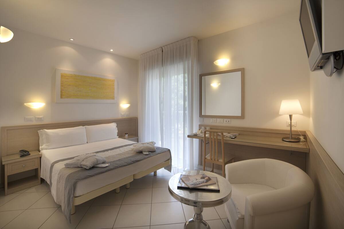 Une chambre d’hôtel comprenant un lit, une table de chevet, une chaise, un bureau et un grand miroir.