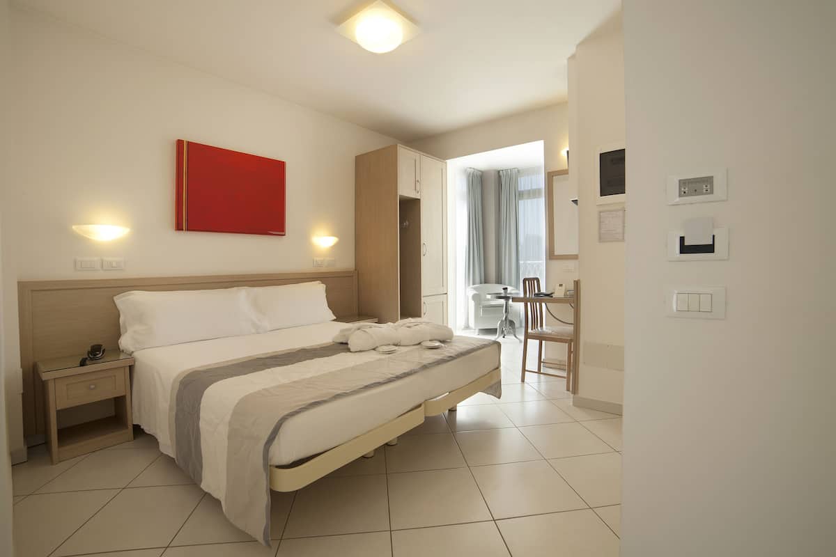 Une chambre d’hôtel moderne avec un grand lit, des tables de chevet, un bureau et une chaise.