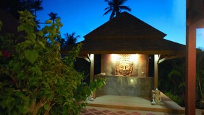 A temple with a Buddha statue, surrounded by greenery and a tiled floor. - Wazzah Resort (Koh Samui)