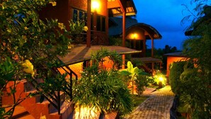 A two-story house with a covered porch and a well-lit garden area. - Wazzah Resort (Koh Samui)