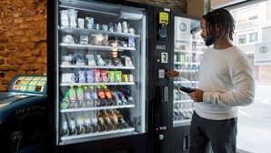 Une personne est en train d’utiliser un distributeur automatique rempli de diverses boissons et de collations.