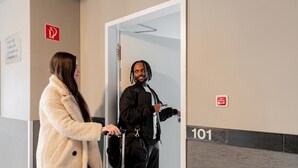 Un couloir d’hôtel avec une porte portant le numéro « 101 » et un panneau d’alarme incendie sur le mur.