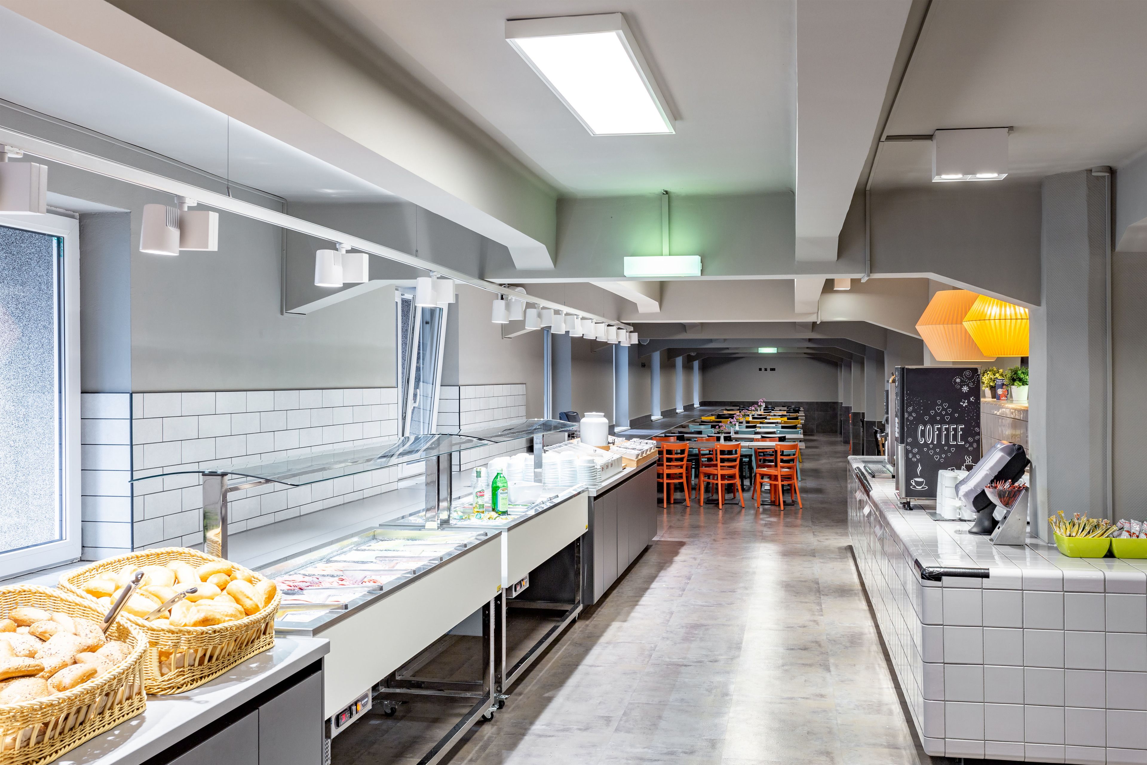 Eine moderne Küche mit einer langen Arbeitsplatte, Brotkörben und einer Kaffeestation.