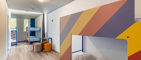 A room with bunk beds, a desk, and a chair.