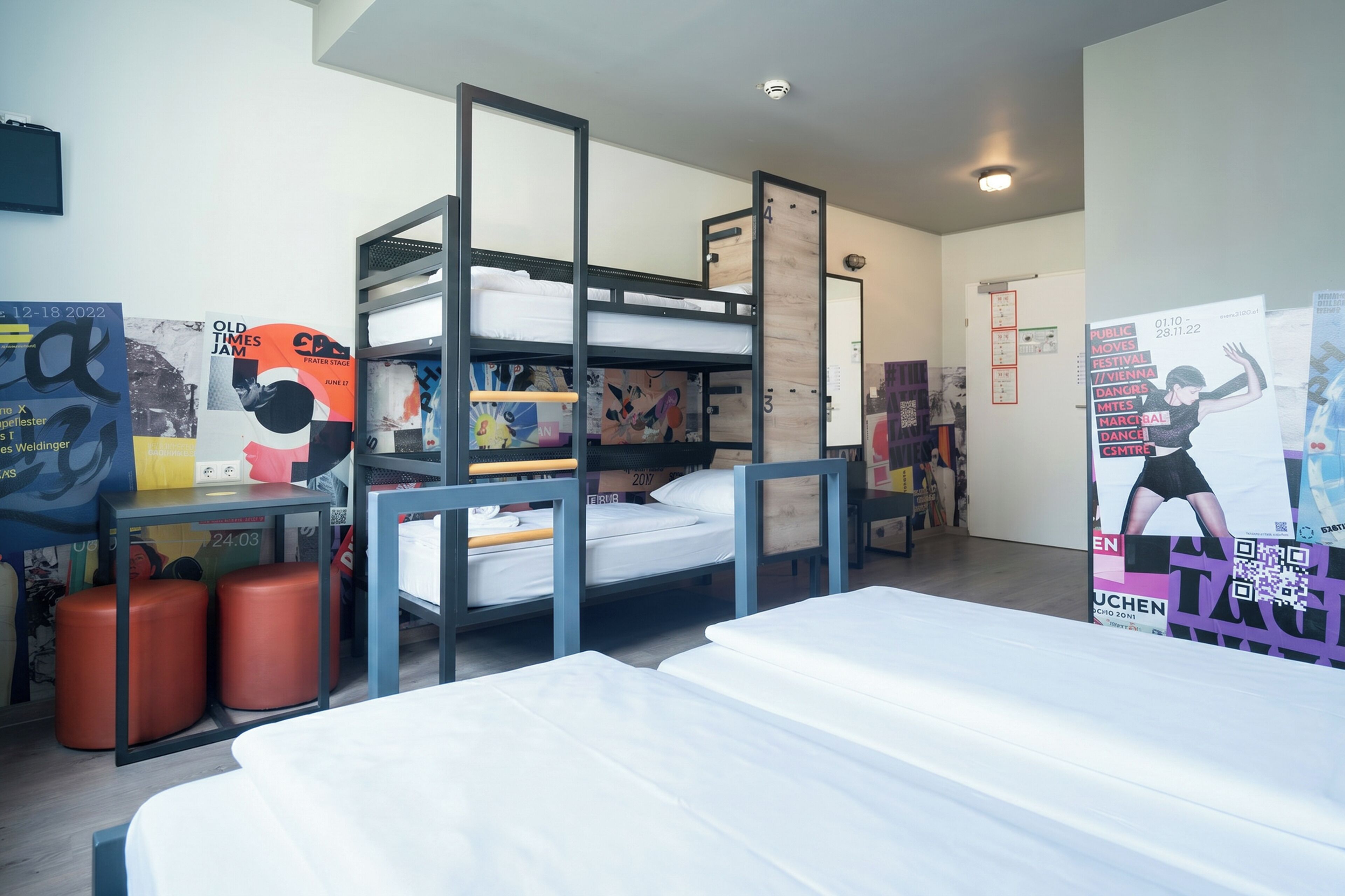 A bunk bed room with a desk, two storage bins, and posters on the walls.