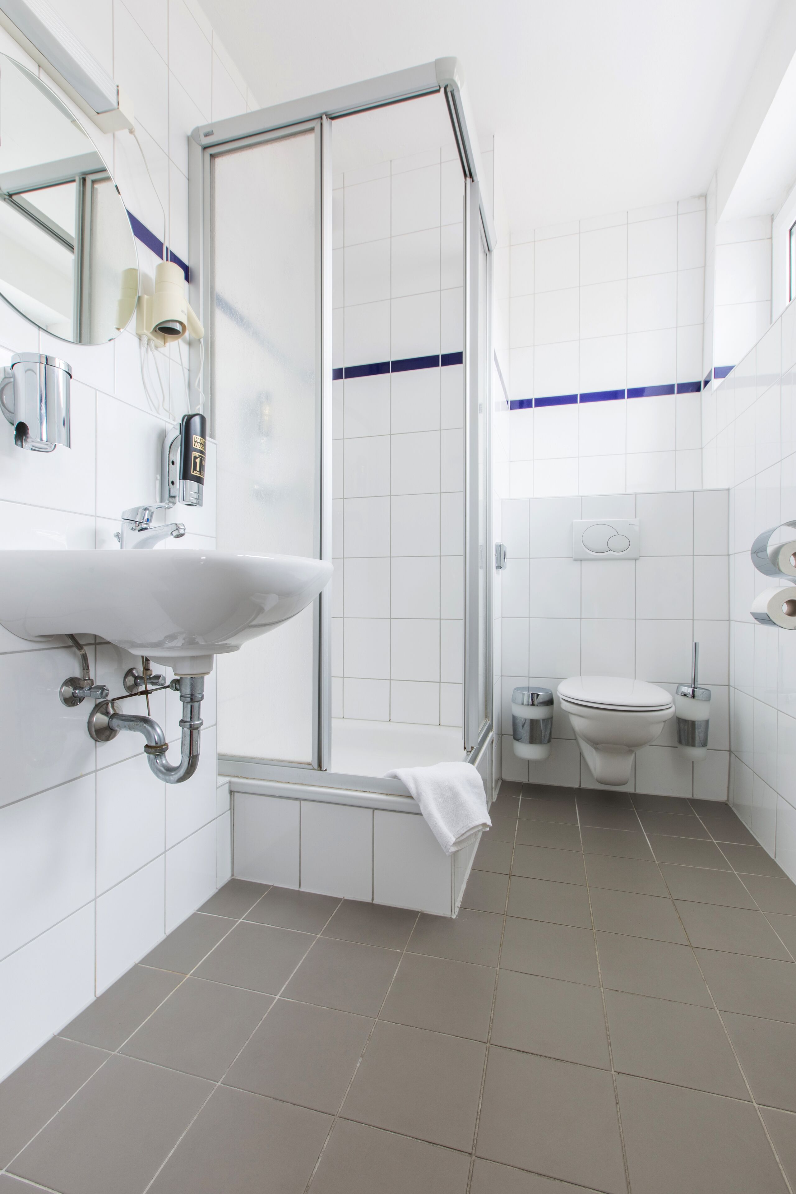 A modern bathroom with a white sink, a toilet, and a glass-enclosed shower.