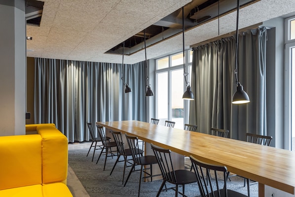 A conference room with a long wooden table, black chairs, and a yellow sofa.