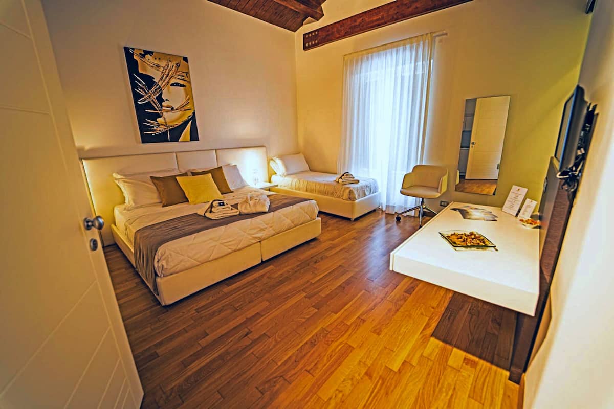A hotel room with a bed, a sofa, a desk, and a chair.
