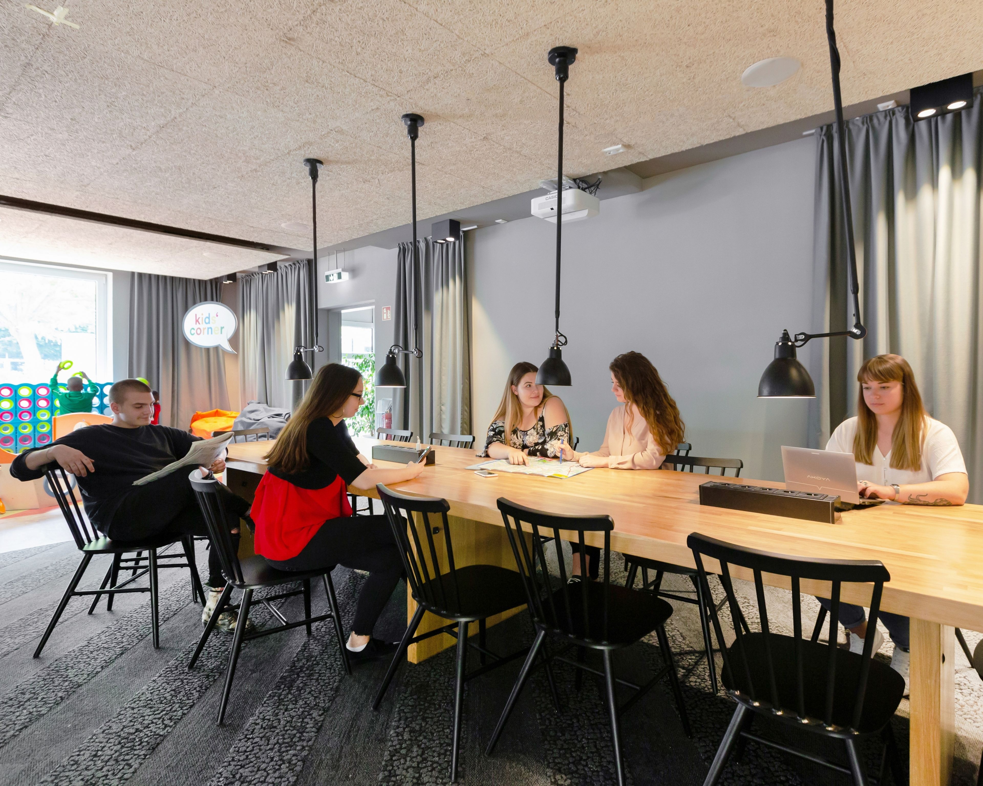 A conference room with a long table, black chairs, and pendant lights.