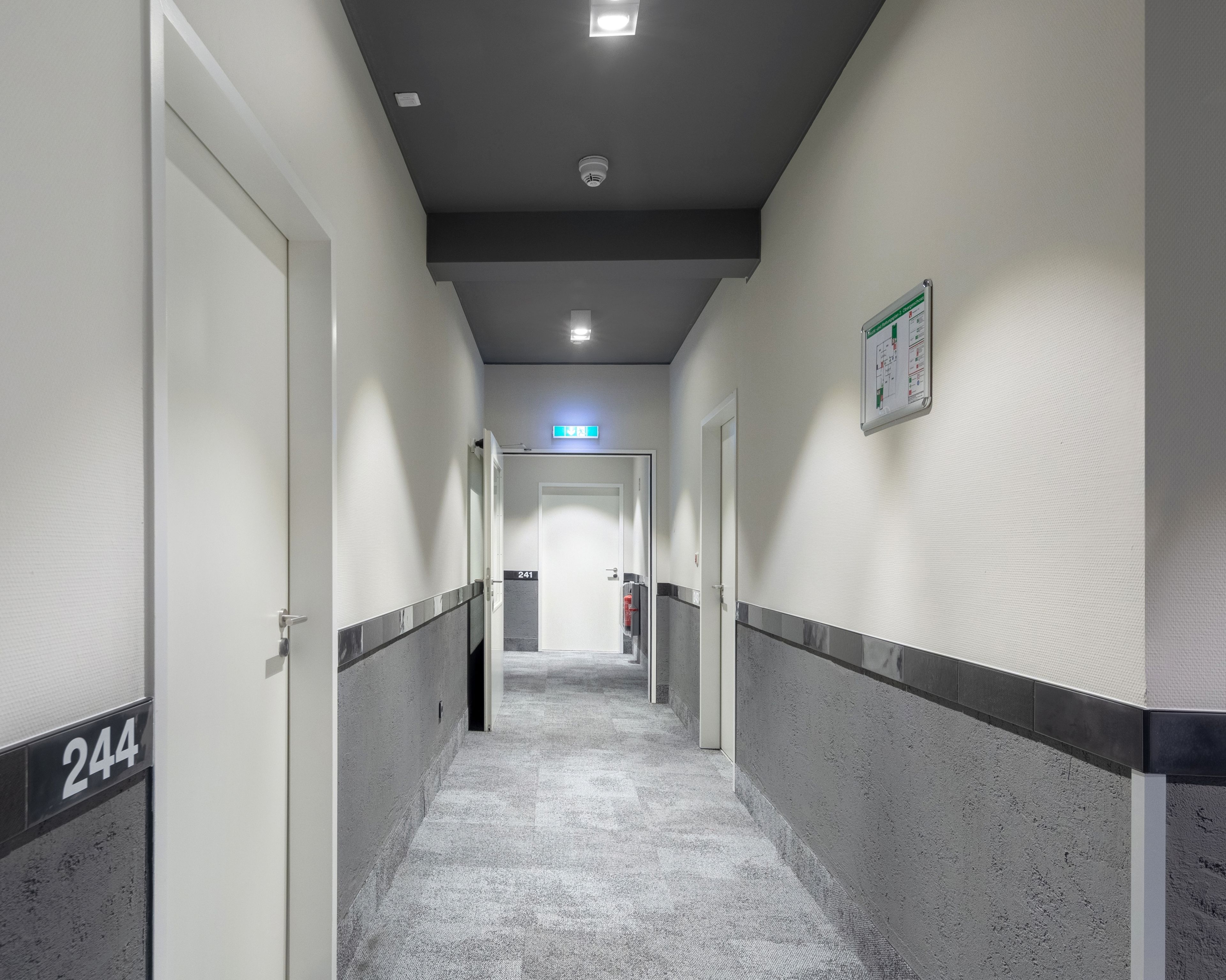 A hallway with doors numbered 244 and 241, a fire extinguisher, and a sign on the wall.