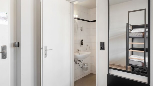 Un baño de hotel con un lavamanos blanco, un espejo y una repisa negra con toallas.