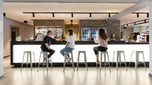 Un área de bar moderna con mostrador, taburetes y un letrero de baño visible.